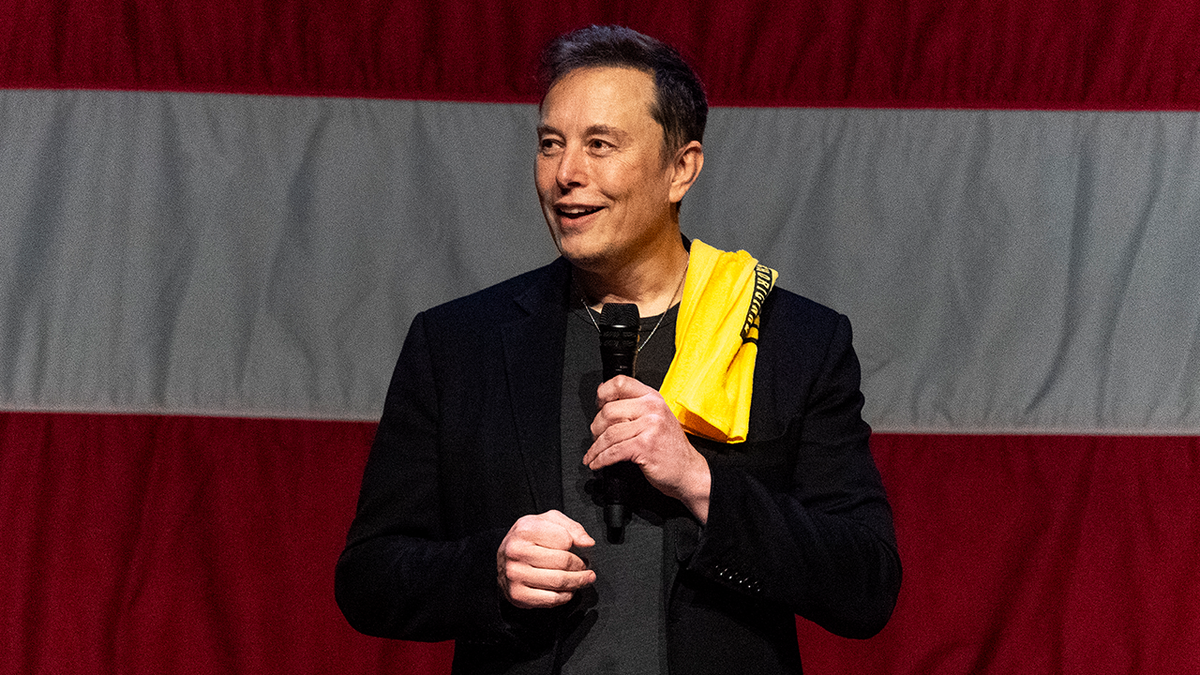 Elon Musk on stage with US flag behind him