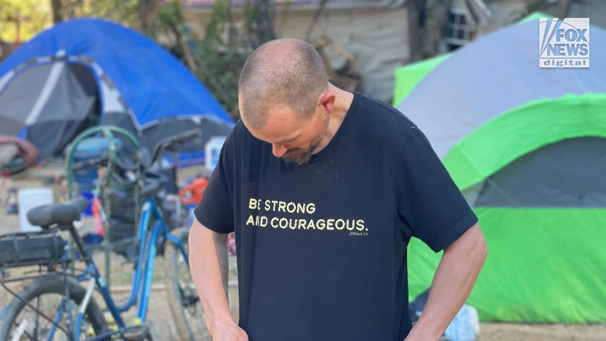 Kris Weil looks at his t-shirt, which reads, "Be strong and courageous"