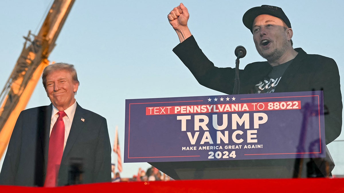 Elon Musk speaking while Donald Trump is standing in the background