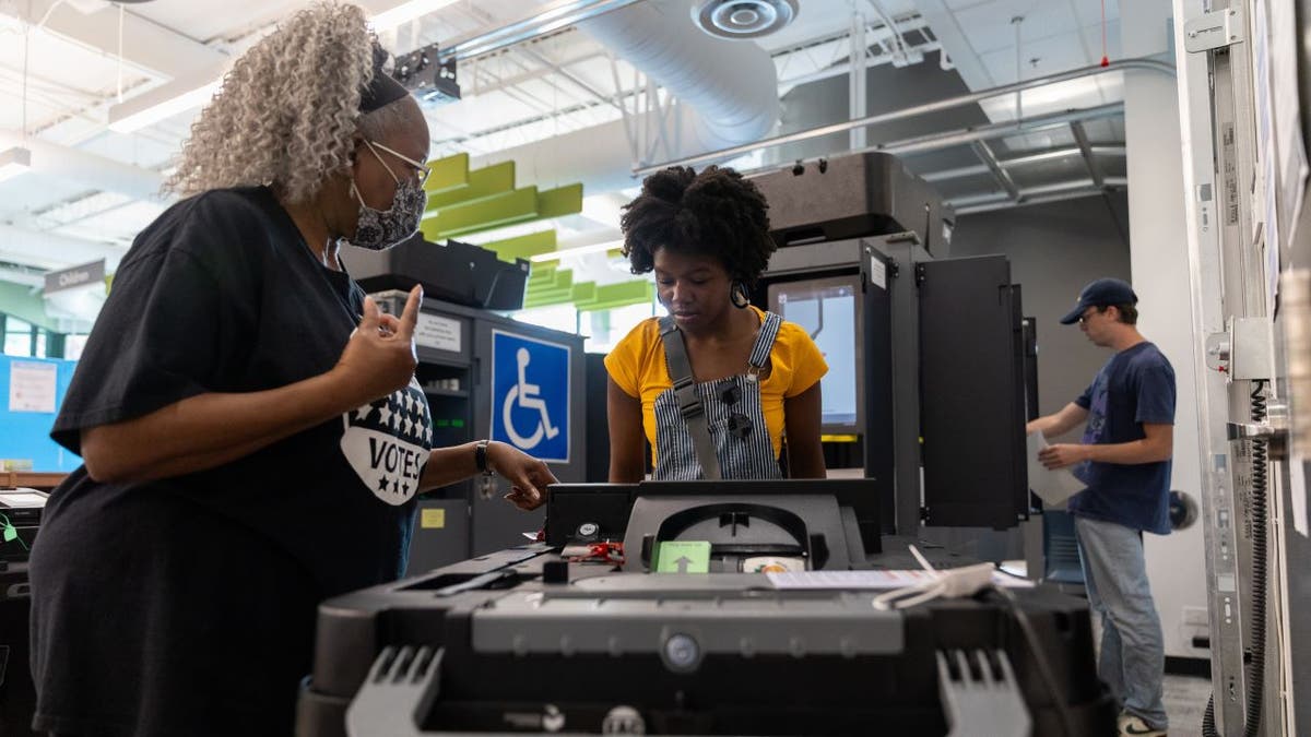 Two women standing near voting machine