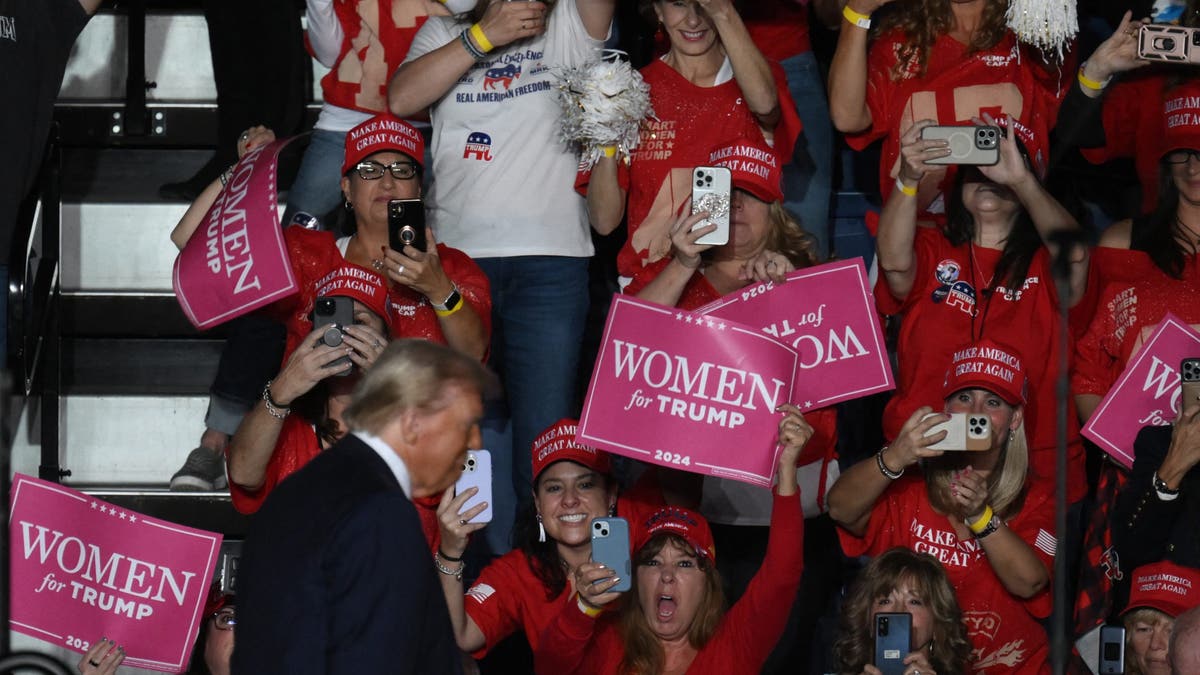 Donald Trump at rally with women holding women for Trump signs behind him