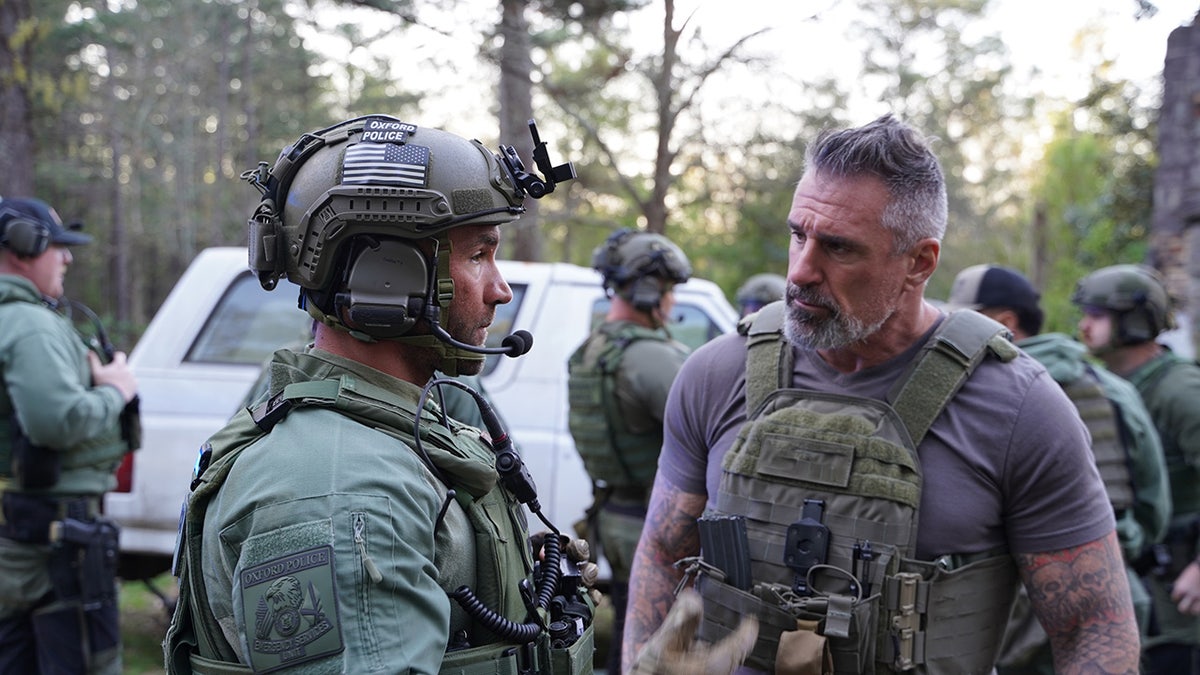 Lou Valouze speaking to an officer in uniform.