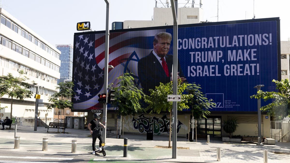 People pass by a congratulatory billboard showing elected U.S. President Donald Trump on Nov. 7, 2024, in Tel Aviv, Israel. 