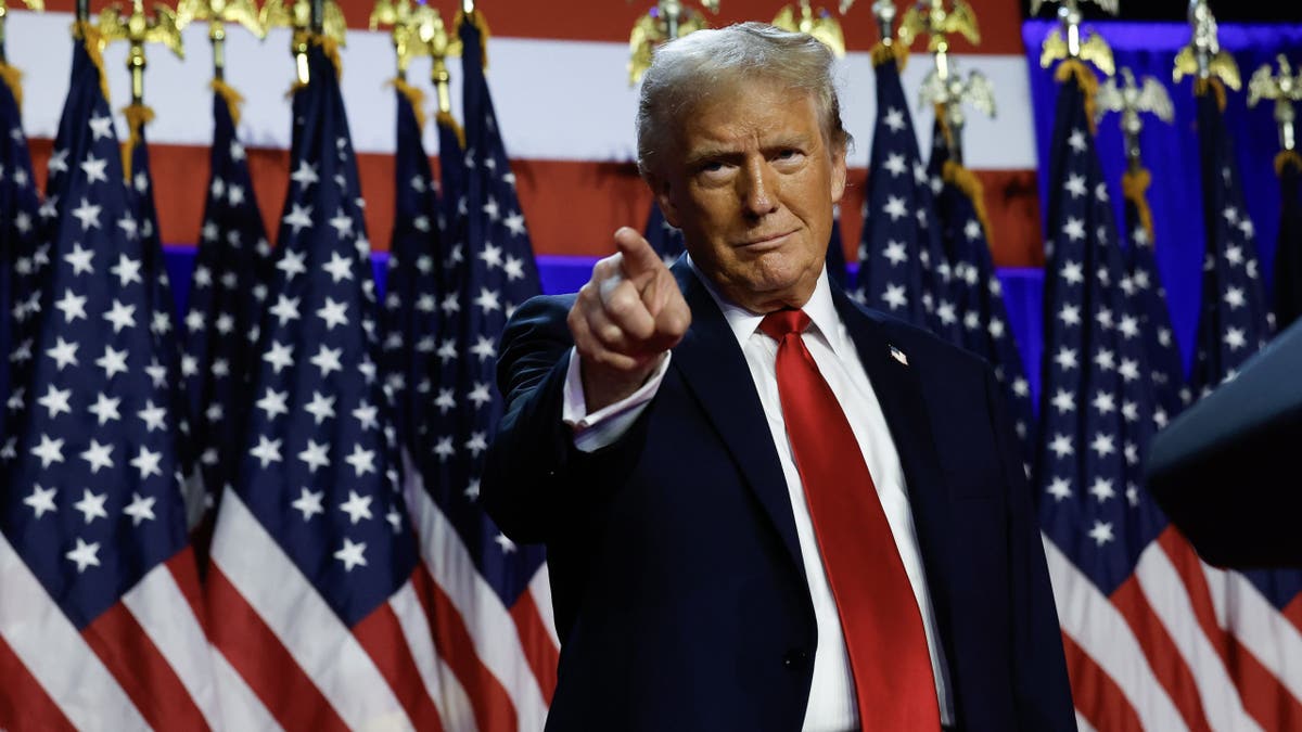 Trump pointing in front of US flags in closeup shot