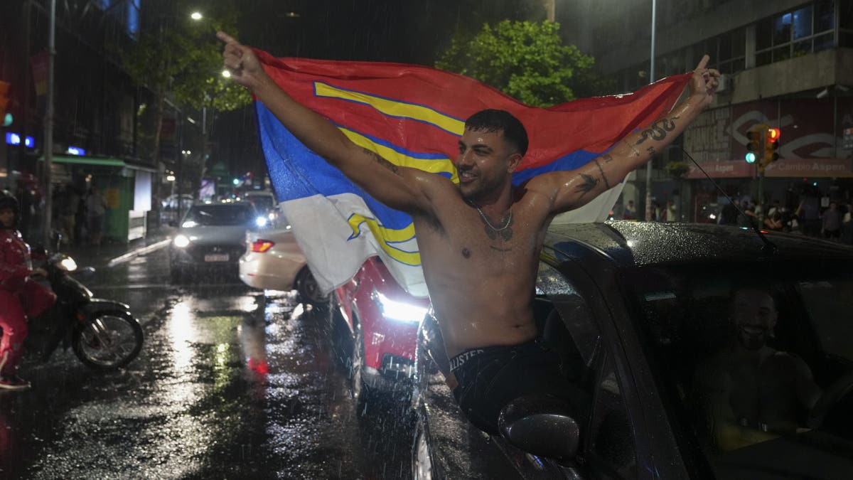 Frente Amplio supporters wave flag out of a car celebrating win