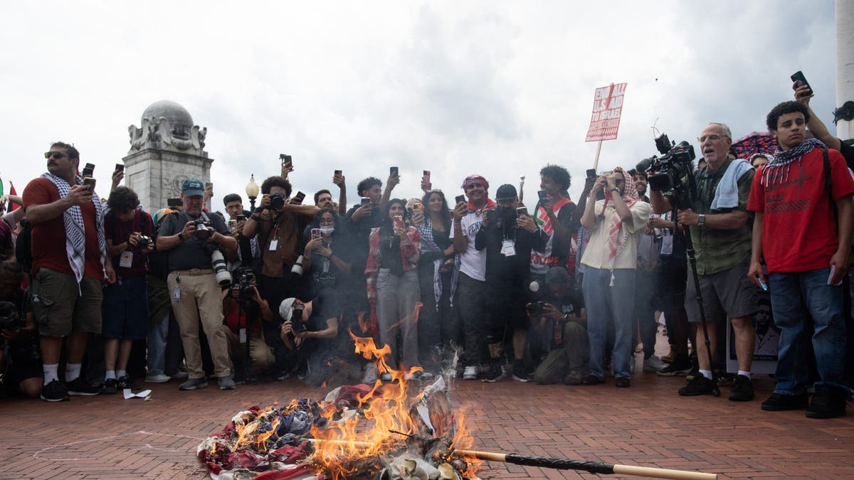 US flag on fire in middle of circle of anti-Israel agitators