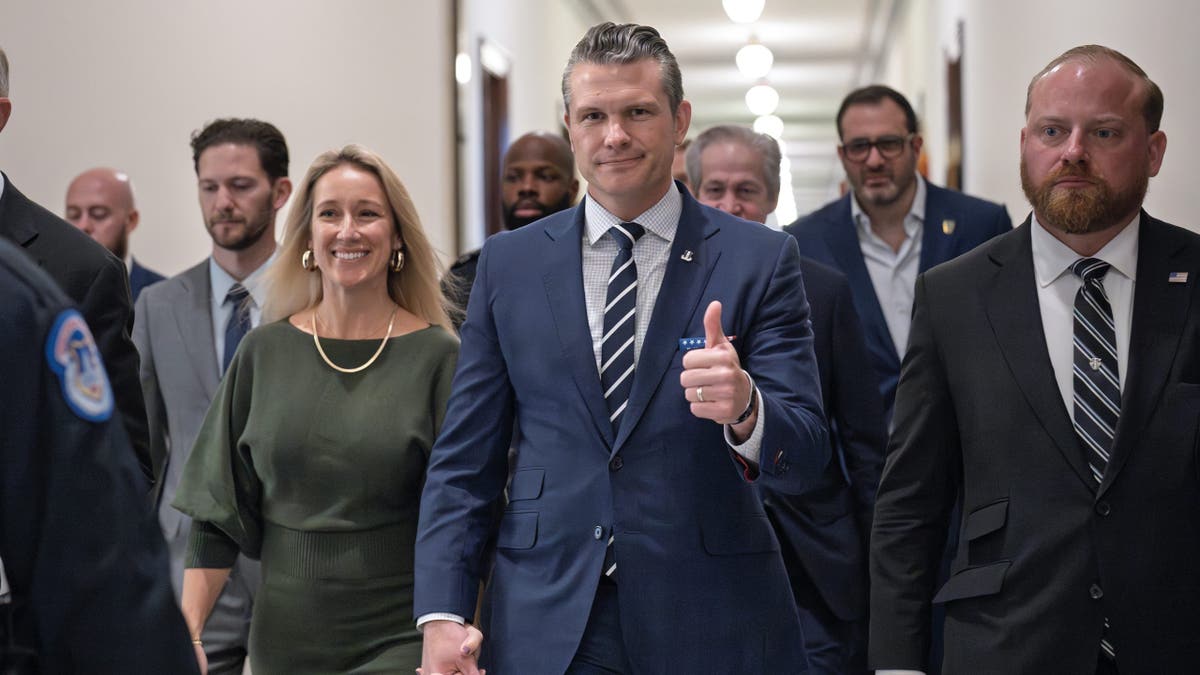 Pete Hegseth gives a thumbs-up as he walks with his wife Jennifer Hegseth to meet with Sen. Joni Ernst at the Capitol on Monday, Dec. 9, 2024.